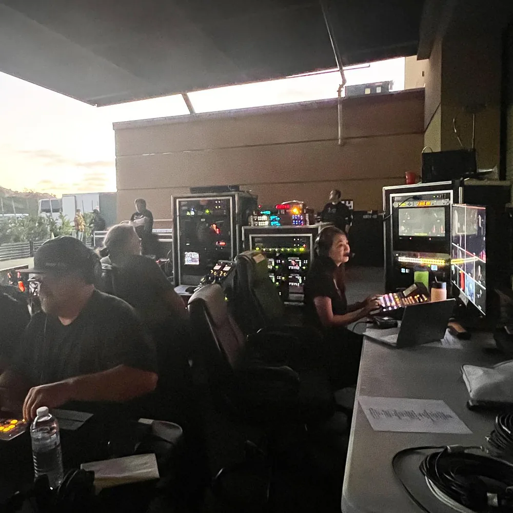 Live show video crew in headsets at their switchers and monitor racks in an open control position at dusk
