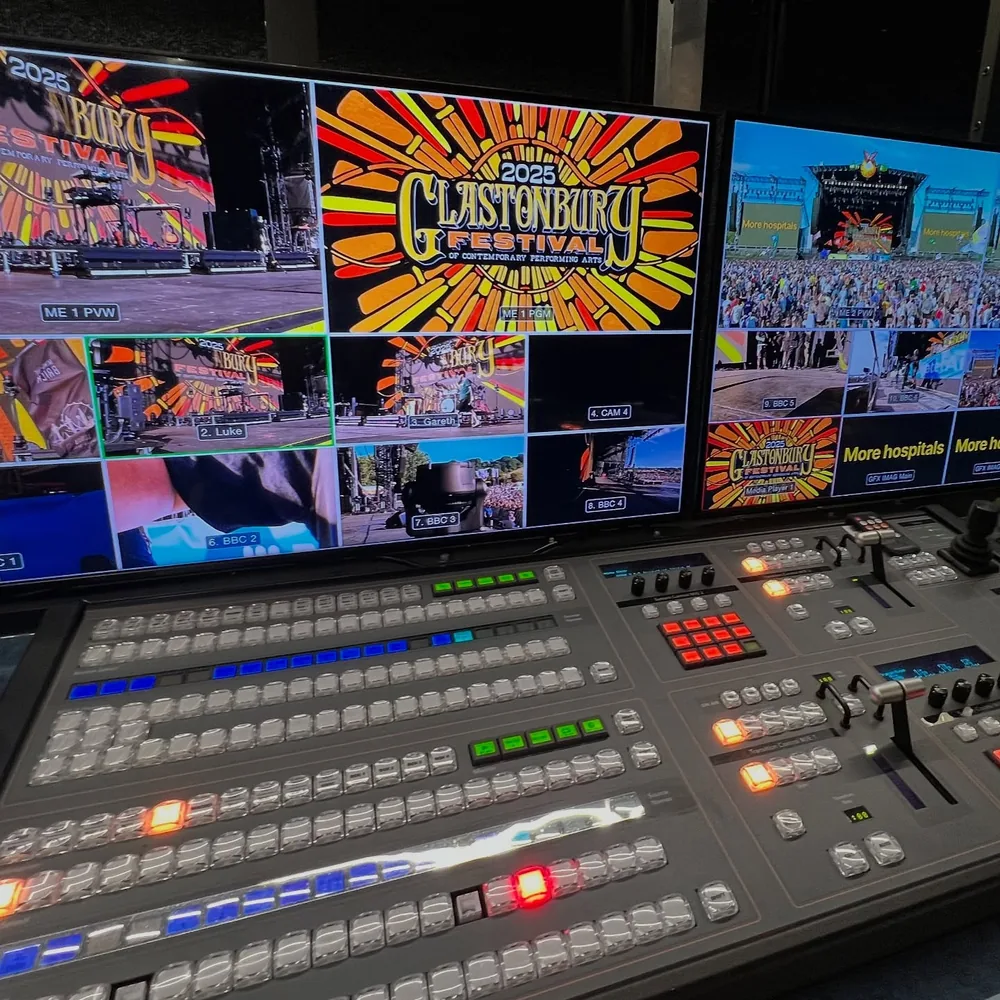 Lit video switcher under multiviewer screens showing festival stage cameras and the program feed